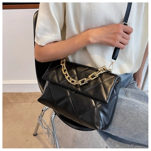Détail du sac bandoulière matelassé noir avec finition brillante et chaîne dorée