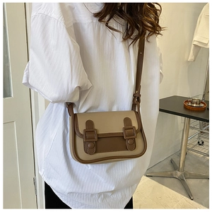 Retro khaki and brown crossbody bag with double buckle straps on white shirt