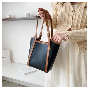 Detail of a large capacity black and brown leather tote bag with adjustable shoulder straps