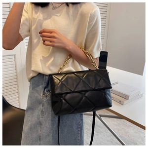 Sac bandoulière noir matelassé avec chaîne dorée porté par un mannequin chic