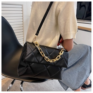 Détail d'un sac bandoulière matelassé noir avec chaîne dorée et fermeture à rabat