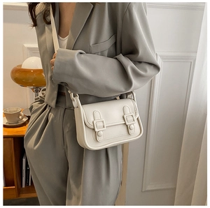 Side view of model wearing a white matte leather square crossbody bag with buckle detail