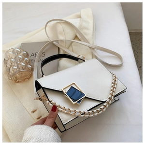 Detail view of white minimalist leather crossbody bag with contrasting black edges and gold buckle