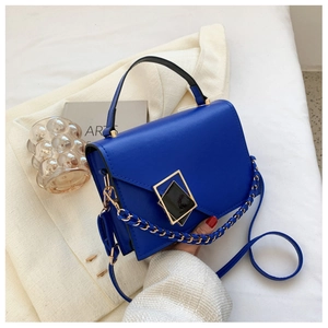 Detail of royal blue textured crossbody bag with gold chain and black leather handle