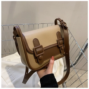 Detail of vintage beige and brown leather crossbody bag with dual buckle closure