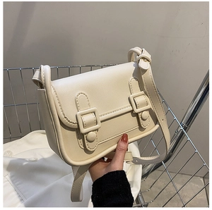 Close-up of a cream matte PU leather flap bag with decorative buckles in a shopping cart