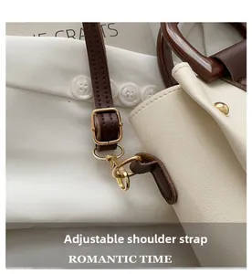 Detail showing adjustable brown leather strap and gold rivet on beige textured handbag