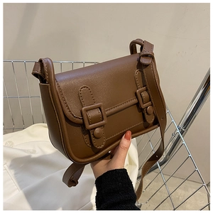 Detail of vintage brown PU leather crossbody bag with double buckle straps and flap