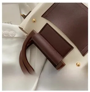 Close-up of contrast color Boston bag with gold rivets and round resin handle