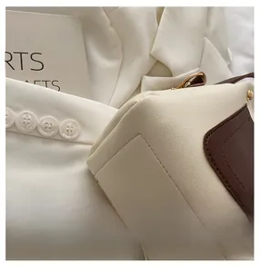 Detailed close-up of premium stitching and brown trim on a cream lychee leather handbag