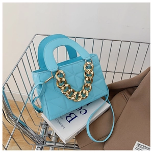 Détail d'un sac à main matelassé bleu ciel avec chaîne dorée dans un caddie argenté