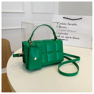 Detail of green quilted crossbody bag with matching detachable coin purse and metal clasp