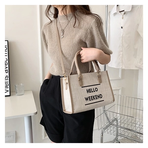 Detail of canvas tote bag featuring Hello Weekend text with adjustable shoulder strap