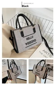 Detail of grey canvas tote bag with HELLO WEEKEND print and black leather straps