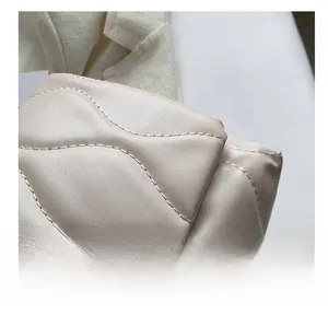 Gros plan détaillé sur les surpiqûres matelassées du sac crème avec boucle dorée