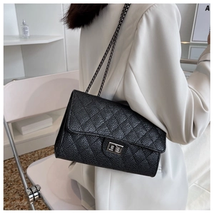 Detail of black quilted chain shoulder bag with metallic twist lock and textured finish