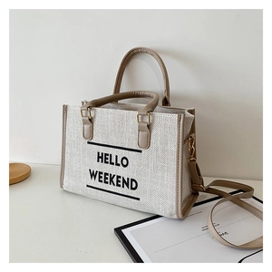 Detail of canvas tote bag with HELLO WEEKEND text and adjustable brown strap