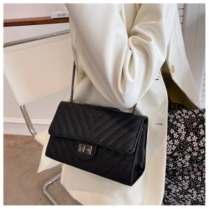 Detail view of black V-quilted texture handbag with metallic chain and turn-lock closure