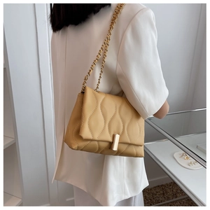 Détail du sac à bandoulière matelassé jaune avec chaîne dorée et boucle magnétique