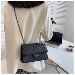 Detail of black chevron quilted leather bag with metallic chain strap and twist lock