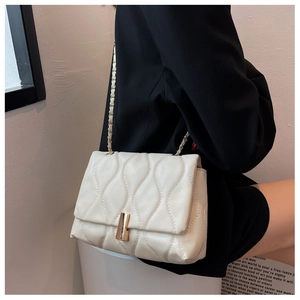 Détail du sac à bandoulière matelassé blanc avec motif ondulé et chaîne dorée