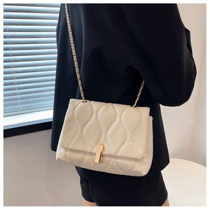 Détail du sac bandoulière matelassé crème avec fermoir doré et bandoulière chaîne en cuir