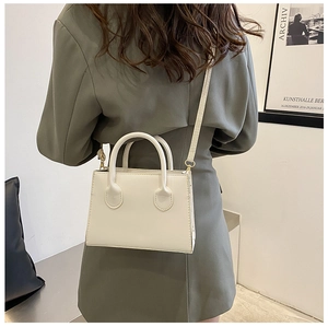 Minimalist white mini rectangular handbag with top handles and golden hardware detail