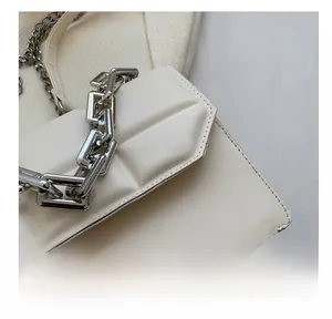 Détail macro des coutures précises et de la chaîne argentée sur le sac bandoulière blanc