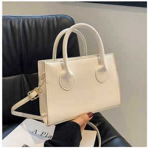 Macro view of cream white leather handbag featuring gold metal buckles and cylindrical handles