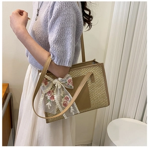 Dettaglio della borsa tote in paglia con finiture in pelle e grande fiocco in pizzo floreale