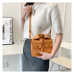 Detail of creative jacket-shaped orange leather mini bag with gold hanger handle