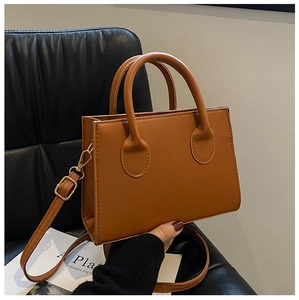 Detailed shot of brown PU leather handbag featuring gold hardware and circular handles
