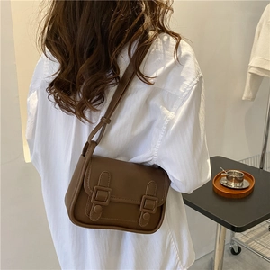Retro dark brown crossbody saddle bag with dual decorative buckles and adjustable strap