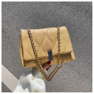 Détail du sac matelassé jaune gingembre avec motif ondulé et chaîne dorée