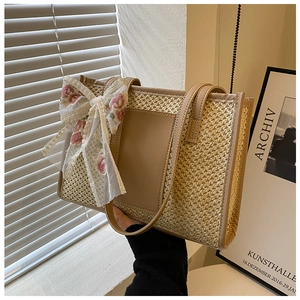 Dettaglio della borsa tote in paglia intrecciata con finiture in pelle marrone e fiocco