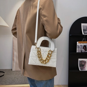 White quilted rectangular handbag with chunky gold chain and leather shoulder strap on model