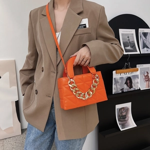 Sac à main matelassé orange avec chaîne et bandoulière porté par un mannequin femme