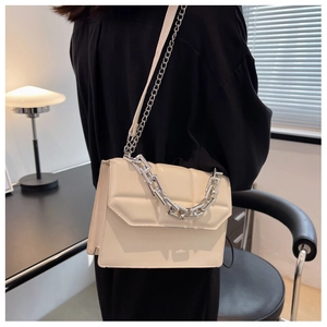 Détail du sac crème avec une grosse chaîne argentée et un design à rabat texturé