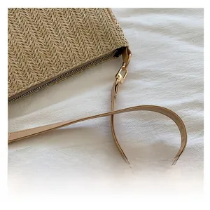 Close-up of woven straw bag featuring a high-quality leather strap and gold zipper detail