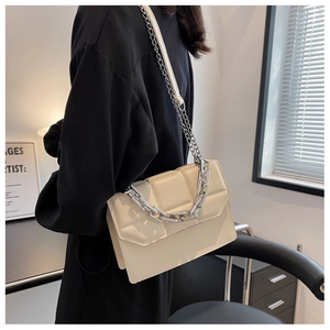 Sac bandoulière beige chic avec grosse chaîne argentée porté par un mannequin