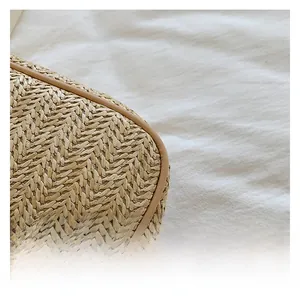 Close-up of woven straw bag showing tight cross-stitch texture and brown leather trim