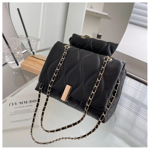 Détail d'un sac à bandoulière matelassé noir avec chaîne dorée et fermoir en métal