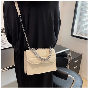 Détail d'un sac bandoulière beige matelassé avec chaîne argentée et texture en cuir PU