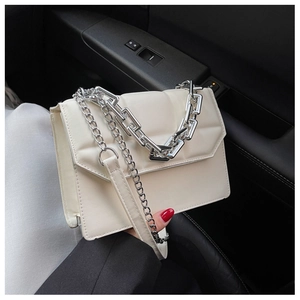 Détail d'un sac à main crème avec chaîne en métal argenté sur un fond intérieur sombre
