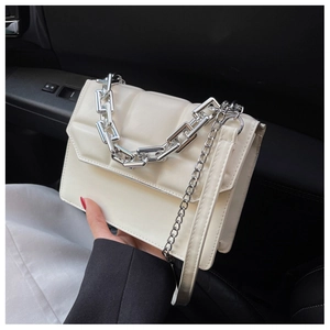 Détail du sac bandoulière blanc matelassé avec chaîne argentée sur intérieur de voiture