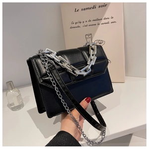 Détail du sac à bandoulière matelassé noir avec poignée et sangle en chaîne argentée