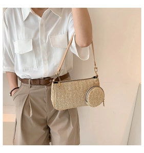 Detail of woven straw shoulder bag featuring smooth leather strap and round coin purse charm