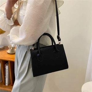 Minimalist black leather handbag for women featuring gold hardware and a top handle