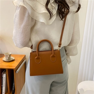 Brown square leather crossbody handbag for women with adjustable strap on white outfit