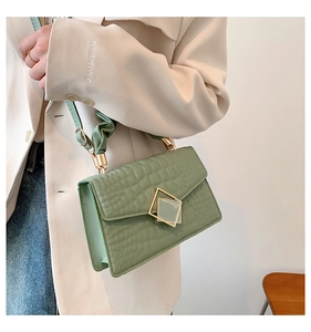Détail du sac à main vert herbe à texture crocodile, boucle dorée et poignée plissée